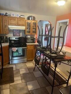 2928 Austin St, Muskegon, MI 49444 - kitchen featuring stainless steel range, under cabinet range hood, light countertops, and glass insert cabinets