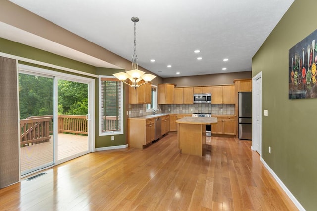 1995 Shining Tree Dr NE, Belmont, MI 49306 - kitchen with stainless steel appliances, light countertops, light wood-style flooring, decorative backsplash, and a kitchen island