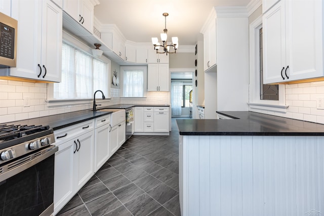820 N Johnson St, Bay City, MI 48708 - kitchen featuring appliances with stainless steel finishes, a chandelier, dark countertops, tasteful backsplash, and crown molding