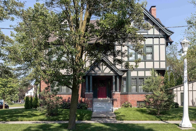820 N Johnson St, Bay City, MI 48708 - english style home with brick siding, a front lawn, a chimney, and stucco siding