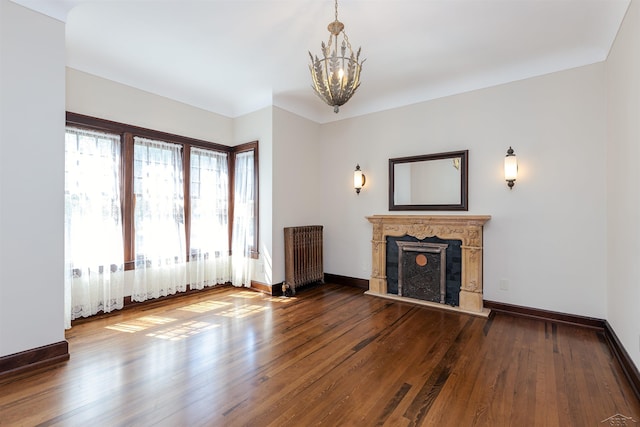 820 N Johnson St, Bay City, MI 48708 - unfurnished living room featuring a chandelier, wood finished floors, a fireplace with raised hearth, and radiator