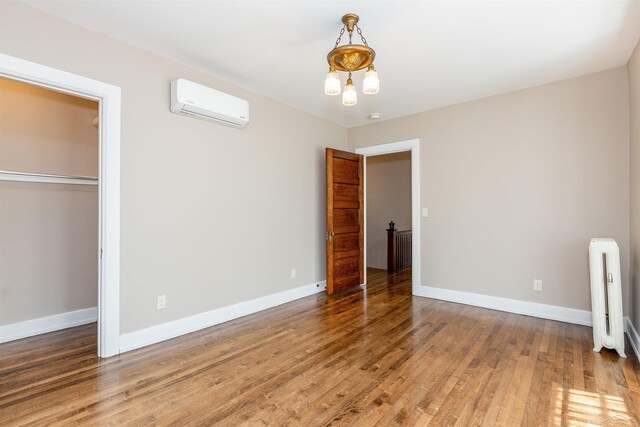 820 N Johnson St, Bay City, MI 48708 - unfurnished bedroom with a wall mounted air conditioner, radiator heating unit, wood finished floors, and a closet