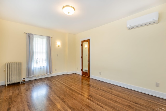 820 N Johnson St, Bay City, MI 48708 - spare room with radiator heating unit, a wall mounted air conditioner, and wood finished floors