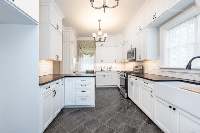 820 N Johnson St, Bay City, MI 48708 - kitchen featuring appliances with stainless steel finishes, a chandelier, dark countertops, and white cabinets