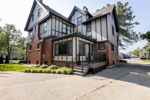 820 N Johnson St, Bay City, MI 48708 - tudor-style house featuring brick siding, a chimney, and roof with shingles