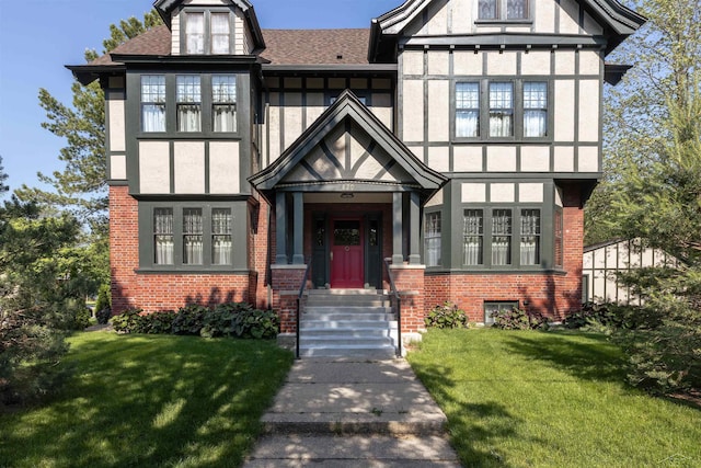 820 N Johnson St, Bay City, MI 48708 - tudor-style house with a front yard, brick siding, a shingled roof, and stucco siding