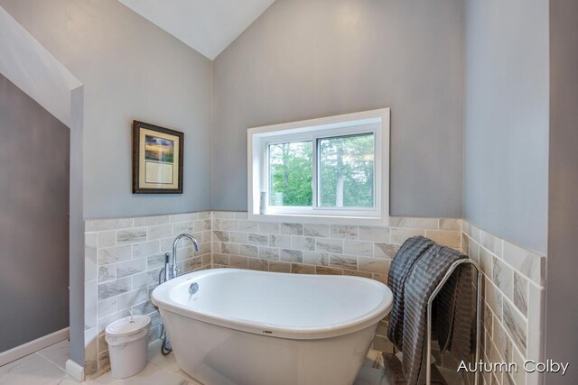 5980 Division St, Newaygo, MI 49337 - bathroom featuring tile walls, a freestanding bath, vaulted ceiling, and wainscoting