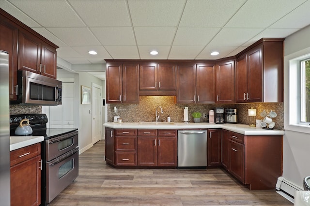1105 W Genesee St, Frankenmuth, MI 48734 - kitchen featuring appliances with stainless steel finishes, baseboard heating, light wood-type flooring, light countertops, and a paneled ceiling