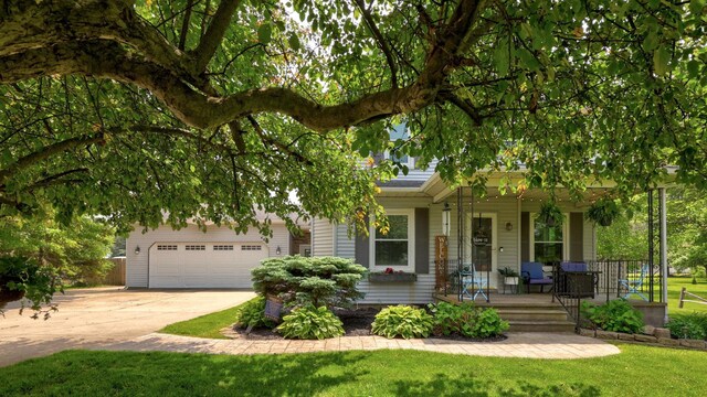 1105 W Genesee St, Frankenmuth, MI 48734 - view of property hidden behind natural elements featuring covered porch, concrete driveway, a front yard, and an attached garage