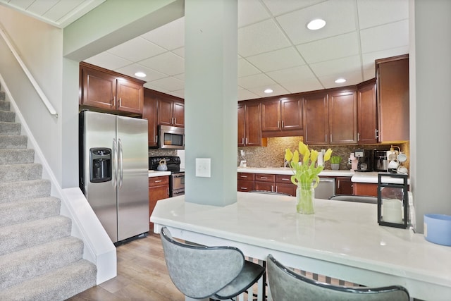 1105 W Genesee St, Frankenmuth, MI 48734 - kitchen featuring appliances with stainless steel finishes, light countertops, a breakfast bar, decorative backsplash, and recessed lighting