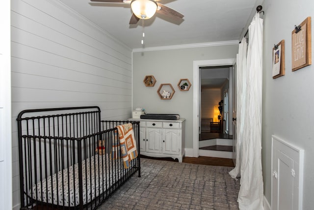 1303 Homecrest Ave, Kalamazoo, MI 49001 - bedroom with crown molding, a crib, ceiling fan, and wooden walls