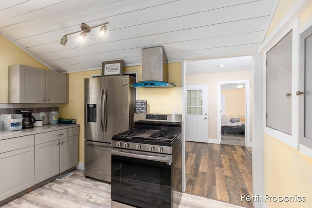 340 E Main St SE, Caledonia, MI 49316 - kitchen featuring wall chimney exhaust hood, appliances with stainless steel finishes, gray cabinets, light wood-style floors, and lofted ceiling