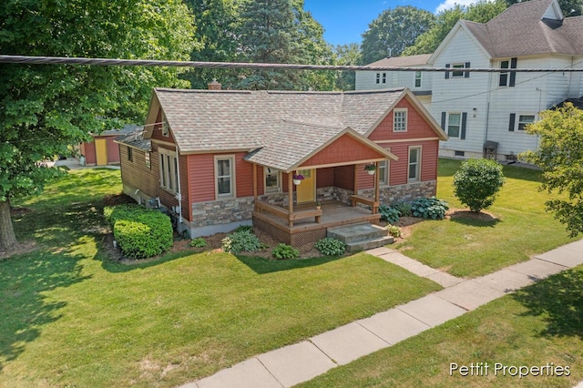 340 E Main St SE, Caledonia, MI 49316 - view of front of house featuring stone siding, a front yard, a chimney, a porch, and a shingled roof