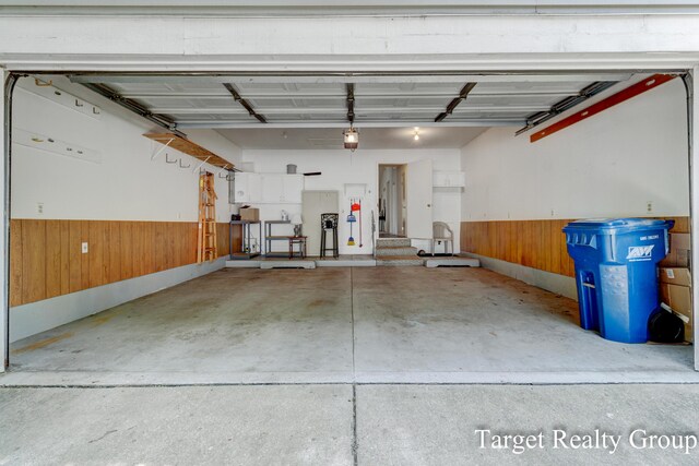 271 Rolling Greene Dr NW, Grand Rapids, MI 49534 - garage with wooden walls, a wainscoted wall, and a garage door opener