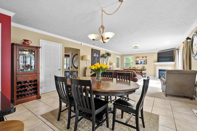 16069 Grazenview St, Schoolcraft, MI 49087 - dining area featuring light tile patterned floors, crown molding, a textured ceiling, a glass covered fireplace, and a chandelier