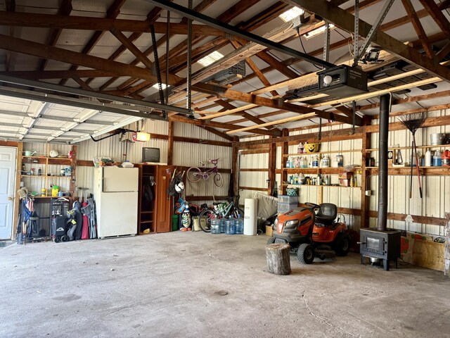 15030 N A Dr N, Marshall, MI 49068 - garage featuring freestanding refrigerator, a wood stove, and a garage door opener