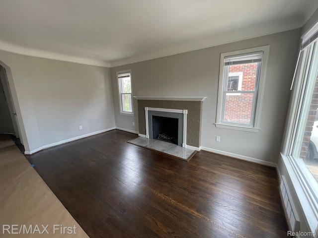 21128 Kenmore Ave, Harper Woods, MI 48225 - unfurnished living room featuring dark wood-style flooring, a fireplace with raised hearth, and arched walkways