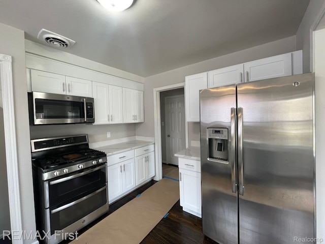 21128 Kenmore Ave, Harper Woods, MI 48225 - kitchen featuring stainless steel appliances, white cabinets, dark wood-style floors, and light stone counters