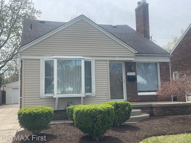 21128 Kenmore Ave, Harper Woods, MI 48225 - view of front of home featuring a shingled roof, a chimney, brick siding, and a garage
