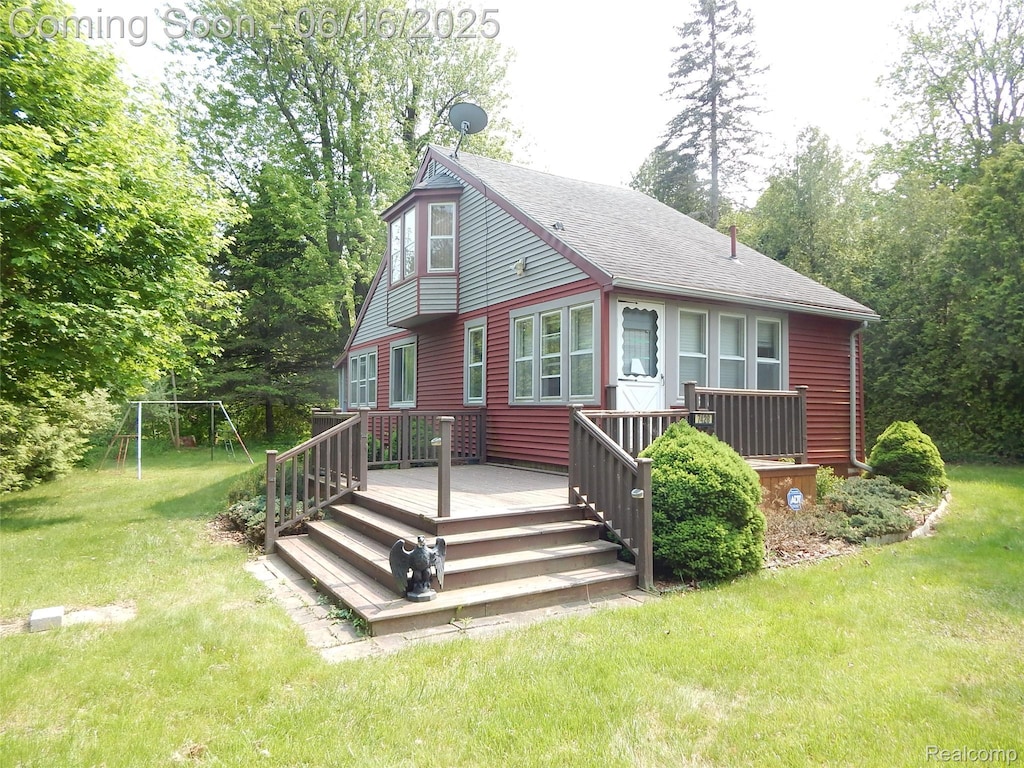 7428 Grove Rd, Lexington, MI 48450 - view of front of property featuring a front lawn, a wooden deck, a playground, and roof with shingles