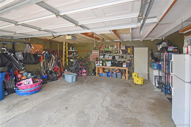 4466 Eastwood Dr, Swartz Creek, MI 48473 - garage with freestanding refrigerator, wooden walls, and a garage door opener