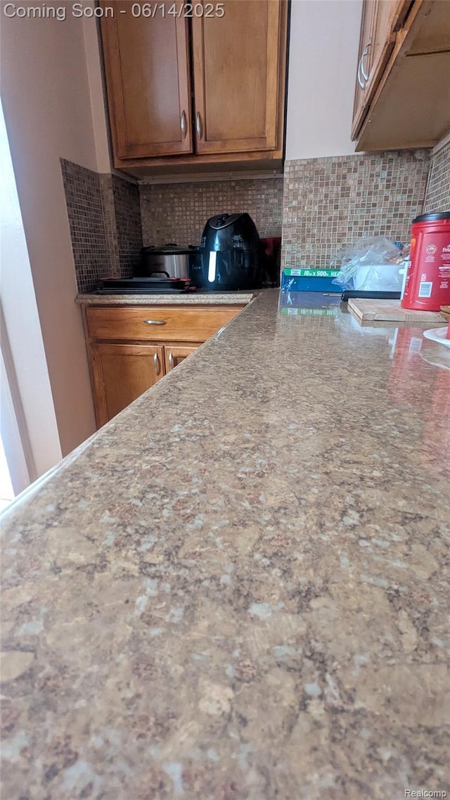 100 Oliver St, Pontiac, MI 48342 - kitchen featuring tasteful backsplash, light stone countertops, and brown cabinetry