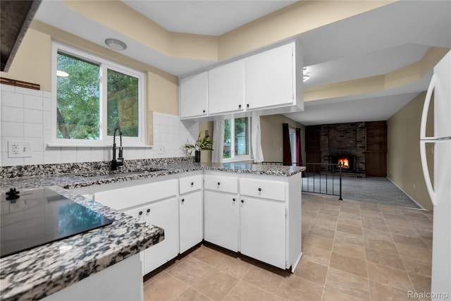 27416 Audrey Ave, Macomb, MI 48092 - kitchen featuring plenty of natural light, light stone countertops, black electric cooktop, and a fireplace