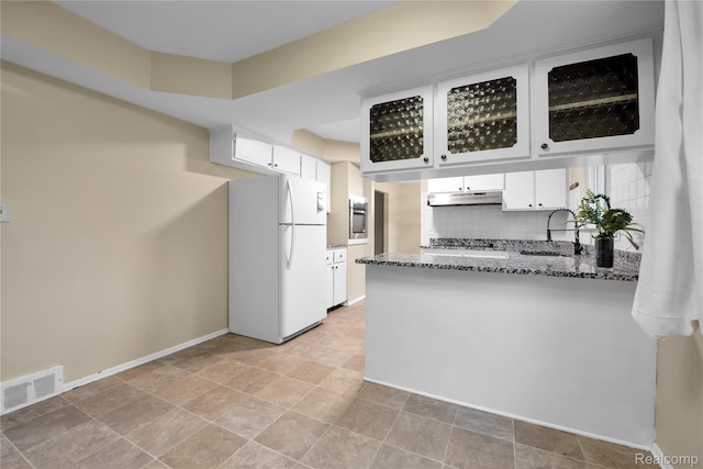 27416 Audrey Ave, Macomb, MI 48092 - kitchen with freestanding refrigerator, a peninsula, dark stone counters, white cabinetry, and backsplash