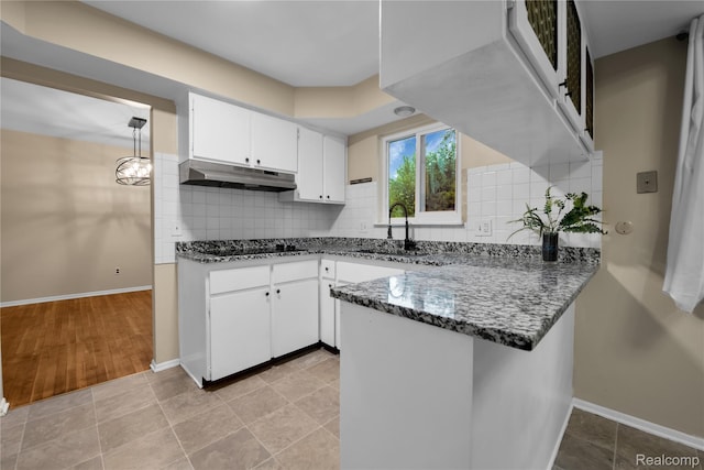 27416 Audrey Ave, Macomb, MI 48092 - kitchen featuring under cabinet range hood, dark stone countertops, a peninsula, white cabinetry, and tasteful backsplash