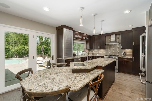 5156 Chestershire Ct, West Bloomfield, MI 48322 - kitchen with wall chimney exhaust hood, stainless steel appliances, tasteful backsplash, hanging light fixtures, and light wood-type flooring