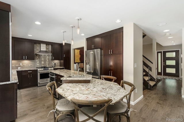 5156 Chestershire Ct, West Bloomfield, MI 48322 - kitchen featuring stainless steel appliances, wall chimney exhaust hood, light wood-style floors, dark brown cabinets, and recessed lighting