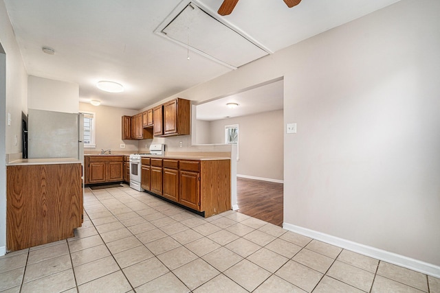 81 Chopin Ave, Troy, MI 48083 - kitchen featuring white range with gas cooktop, brown cabinets, light countertops, light tile patterned flooring, and ceiling fan