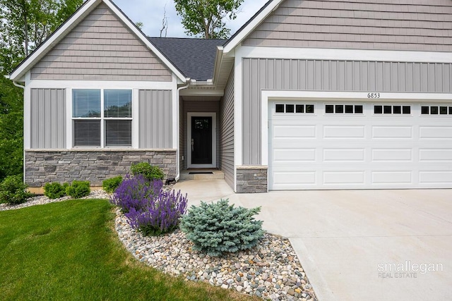 6853 Loggers Ridge Run SE, Caledonia, MI 49316 - view of front of house with stone siding, board and batten siding, driveway, a garage, and a front yard