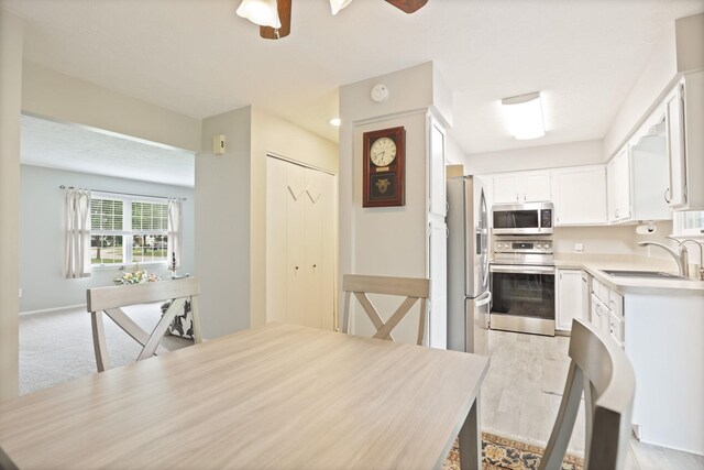 429 Zehnder Dr, Frankenmuth, MI 48734 - kitchen featuring appliances with stainless steel finishes, ceiling fan, light countertops, white cabinets, and light wood finished floors