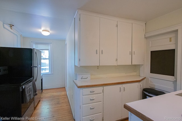 235 E Saint Clair St, Almont, MI 48003 - kitchen featuring light wood finished floors, white cabinetry, light countertops, and freestanding refrigerator