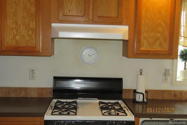 10571 Baraga St, Taylor, MI 48180 - kitchen with gas range gas stove, under cabinet range hood, dark countertops, and brown cabinetry
