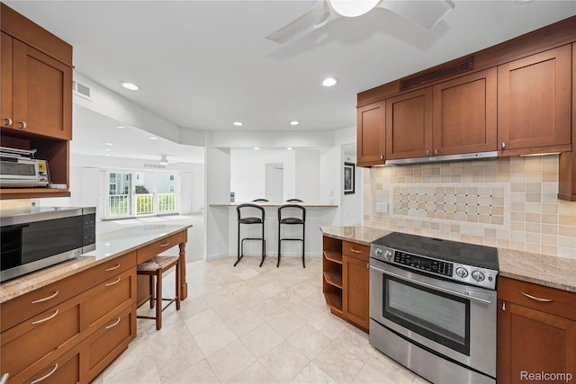 3565 Port Cove Dr Unit 68, Waterford, MI 48328 - kitchen with appliances with stainless steel finishes, ceiling fan, backsplash, light stone countertops, and brown cabinets