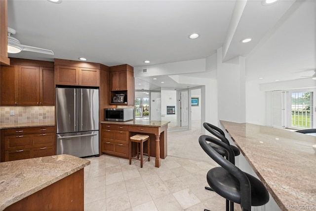 3565 Port Cove Dr Unit 68, Waterford, MI 48328 - kitchen with appliances with stainless steel finishes, a kitchen breakfast bar, a ceiling fan, light stone countertops, and recessed lighting