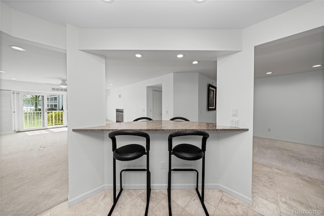 3565 Port Cove Dr Unit 68, Waterford, MI 48328 - kitchen featuring light carpet, dark stone countertops, recessed lighting, a breakfast bar, and a ceiling fan