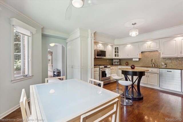 1831 Hampden Rd, Flint, MI 48503 - kitchen with stainless steel appliances, arched walkways, tasteful backsplash, dark wood finished floors, and crown molding