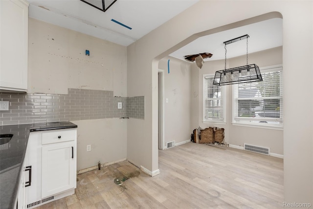 852 Cambridge Rd, Berkley, MI 48072 - kitchen with light wood-type flooring, tasteful backsplash, white cabinetry, decorative light fixtures, and dark countertops