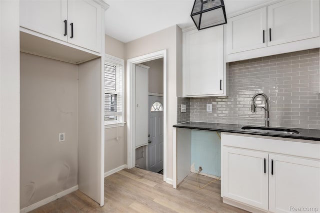 852 Cambridge Rd, Berkley, MI 48072 - kitchen featuring backsplash, dark countertops, light wood-style floors, and white cabinetry