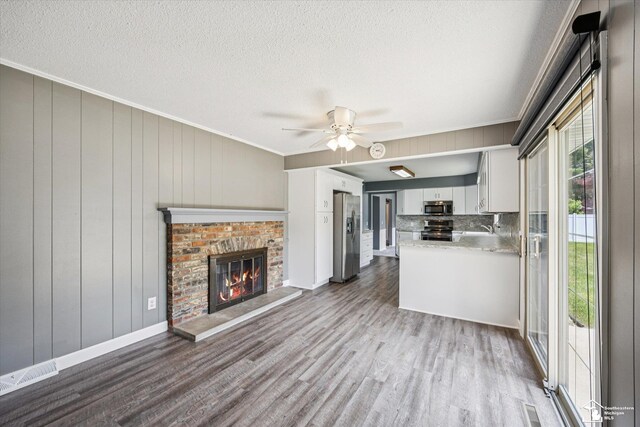 1115 Birchwood Dr, Temperance, MI 48182 - unfurnished living room with dark wood-style floors, a ceiling fan, a fireplace, a textured ceiling, and ornamental molding