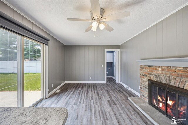 1115 Birchwood Dr, Temperance, MI 48182 - unfurnished living room with wood finished floors, ornamental molding, a brick fireplace, a ceiling fan, and a textured ceiling