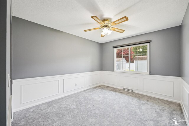 1115 Birchwood Dr, Temperance, MI 48182 - empty room featuring carpet flooring, a wainscoted wall, ceiling fan, a decorative wall, and a textured ceiling