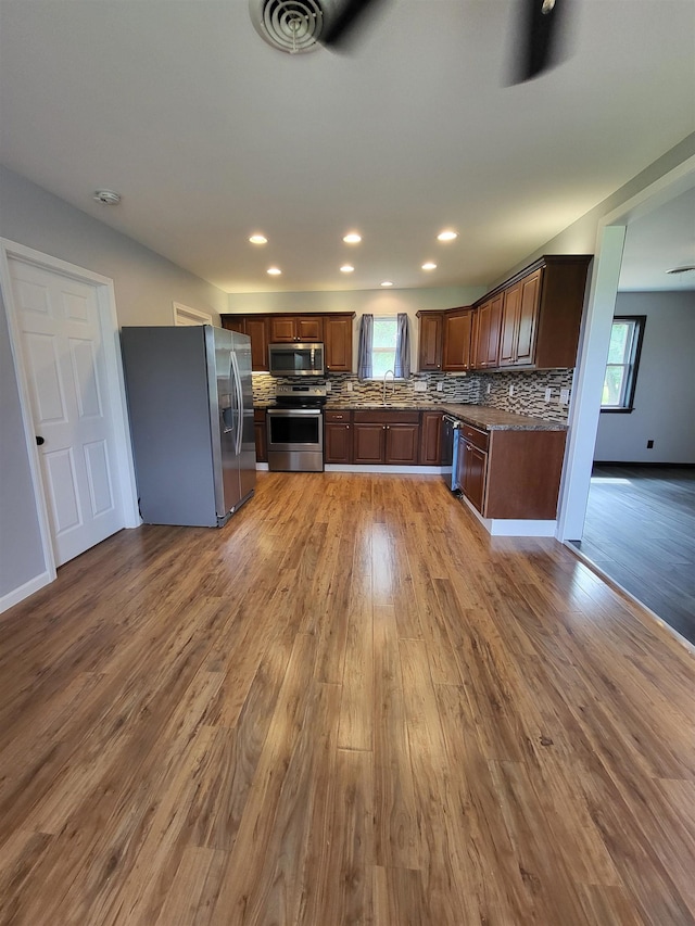 3456 N Irish Rd, Davison, MI 48423 - kitchen featuring appliances with stainless steel finishes, wood finished floors, backsplash, recessed lighting, and dark countertops