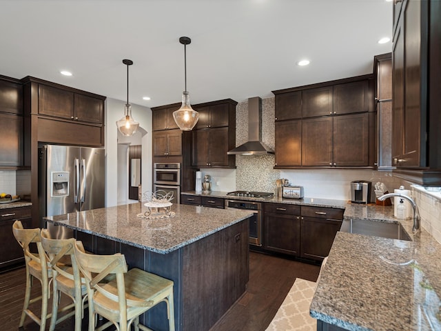 13531 Brampton Ct, Utica, MI 48315 - kitchen featuring wall chimney exhaust hood, appliances with stainless steel finishes, a center island, dark brown cabinetry, and recessed lighting