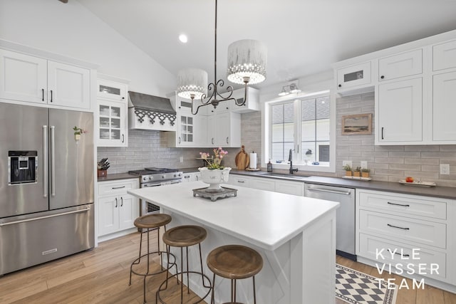3 Woodward Ln SE, Grand Rapids, MI 49506 - kitchen featuring appliances with stainless steel finishes, premium range hood, backsplash, white cabinetry, and light wood finished floors