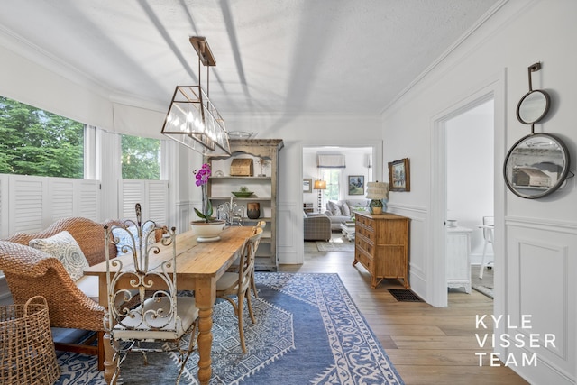 3 Woodward Ln SE, Grand Rapids, MI 49506 - dining room with healthy amount of natural light, crown molding, light wood-style flooring, a chandelier, and wainscoting