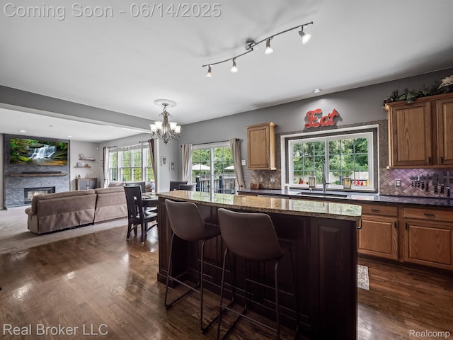 7235 Goldenrod Ct, Brighton, MI 48116 - kitchen with a chandelier, open floor plan, a center island, dark stone counters, and dark wood-style flooring